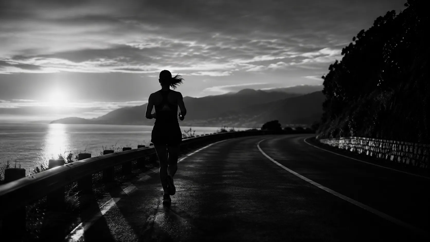 A member running a coastal road at dawn — quiet, consistent, unposed